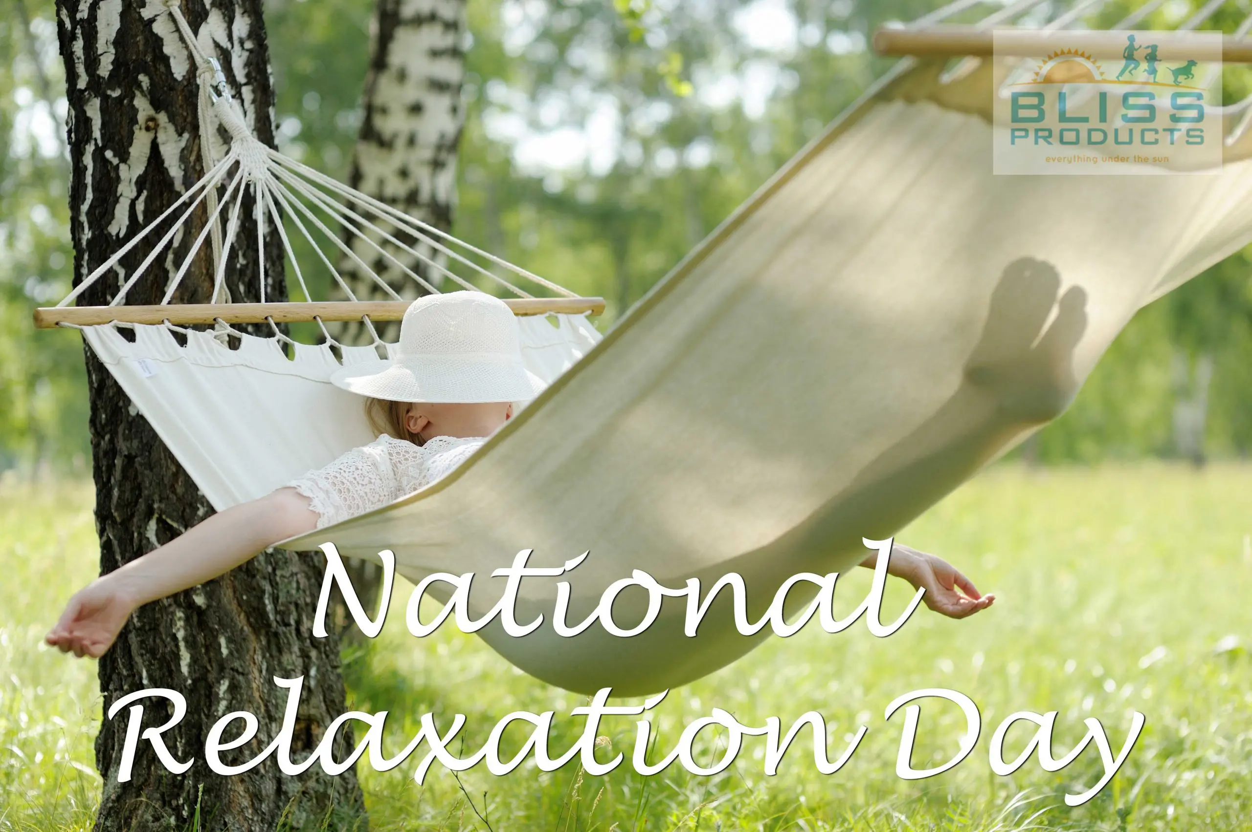 lady in white dress lying in a kaki hammock with a white hat on with arms outstretched in a national park with a background of a field of flowers