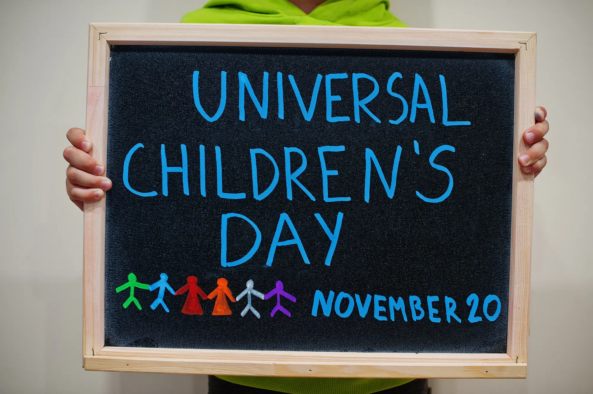chalkboard sign held by child saying Universal Children's Day - November 20