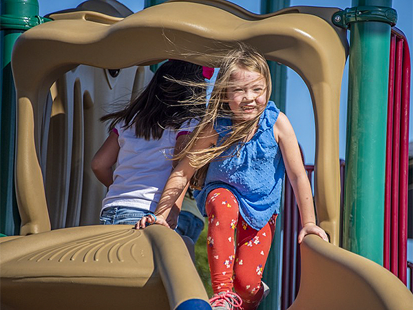 Children sliding and playing on inclusive playground equipment from BPS.