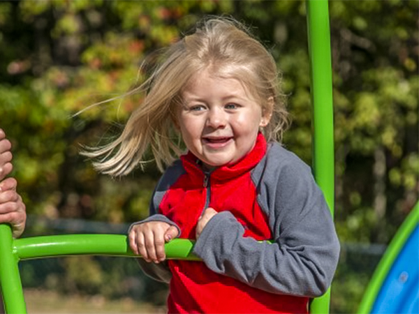Young student enjoying new playground equipment supplied by Bliss Products.