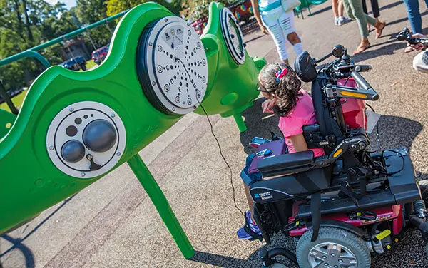 Wheelchair user in Alabama engaging with accessible sensory panels featuring audio and tactile activities, available from Bliss Products and Services in Demopolis, Marengo County.