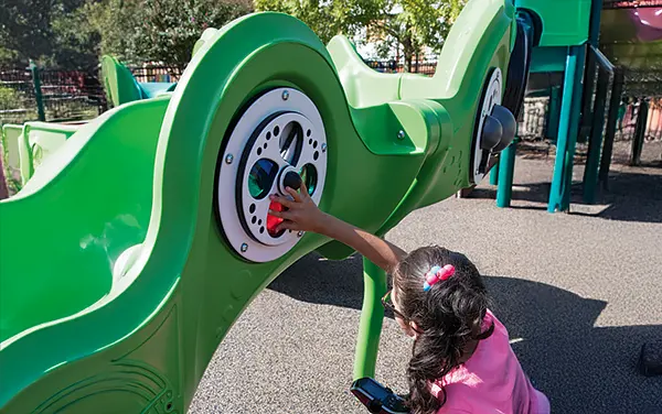 Child in Alabama activating accessible sensory play panels with a large switch on a playground - Shelby County, available from Bliss Products and Services.