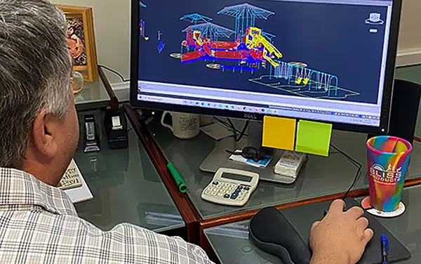 AutoCAD playground layout and 3D rendering on a monitor during a design review at Bliss Products and Services.