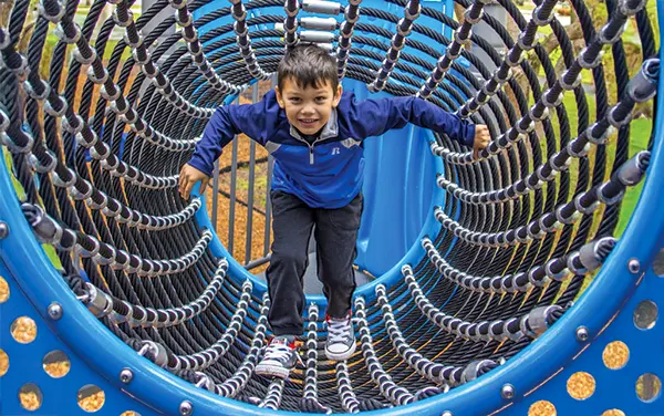 Child crawling through a blue rope tunnel climber in Tallapoosa County, Alabama, available from Bliss Products and Services.