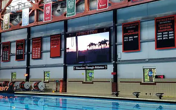 Indoor full-color LED video board displaying scores and graphics at an aquatic center