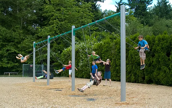 Eight-Bay Single-Post Swing Set Children using an eight-bay single-post swing set on wood mulch.