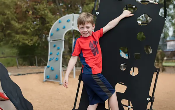 Child using a perforated playground climbing panel in Green crossroads, Barbour County, Alabama, available from Bliss Products and Services.
