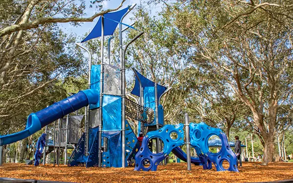 Play structure with slides and climbers under large shade sails,.