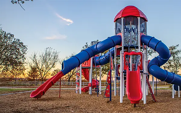 Rocket themed play tower with red and blue slides on engineered wood fiber in Crenshaw County, Alabama, available from Bliss Products and Services.