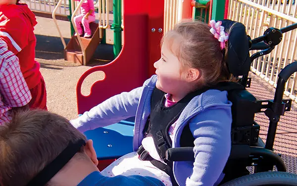 Alabama child using a wheelchair enjoying an accessible playground deck with transfer-friendly design, these decks also encorporate transitions to inclusive, wheelchair swings available from Bliss Products and Services in Flat Rock, Jackson Alabama.