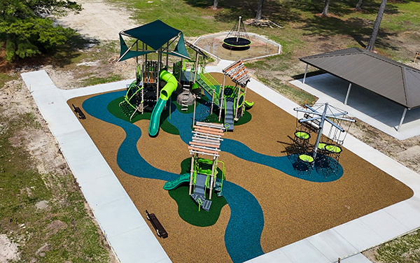 Inclusive play structure with integrated shade sails, slides, and ramp access, available from Bliss Products and Services.