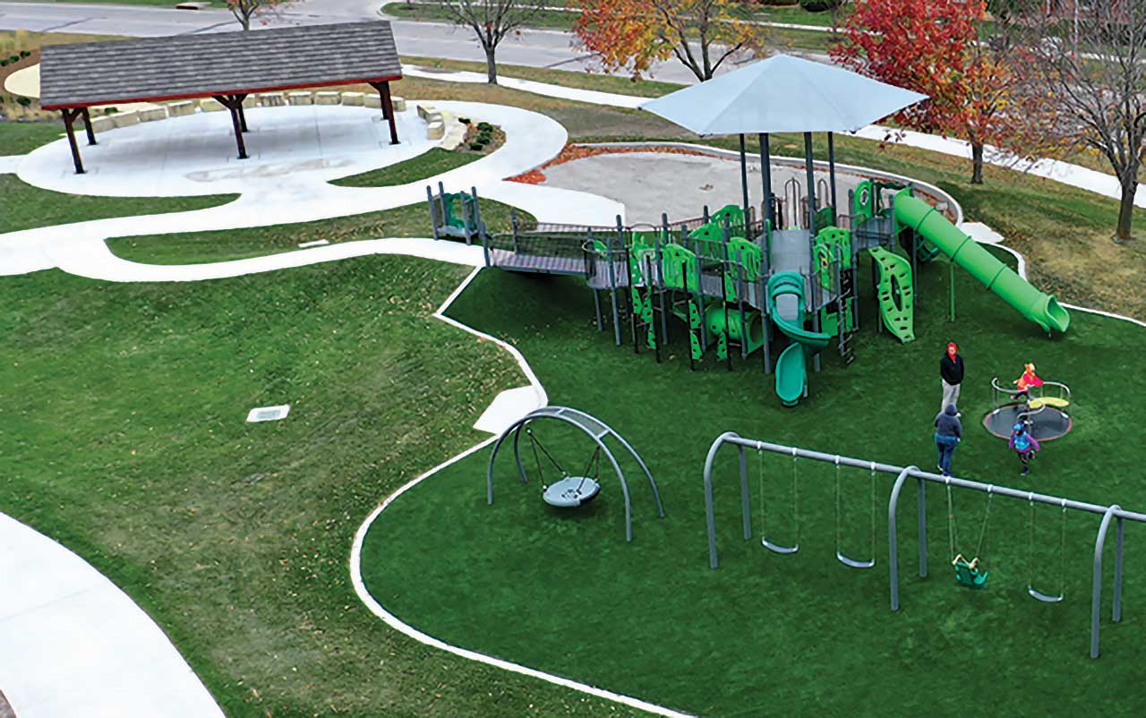 Single-post square umbrella shade over picnic tables on a concrete plaza, available from Bliss Products and Services.