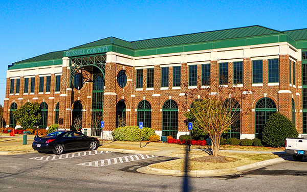 New Russell County Courthouse in Phenix City, Alabama, red-brick facade with green metal roof and arched windows.