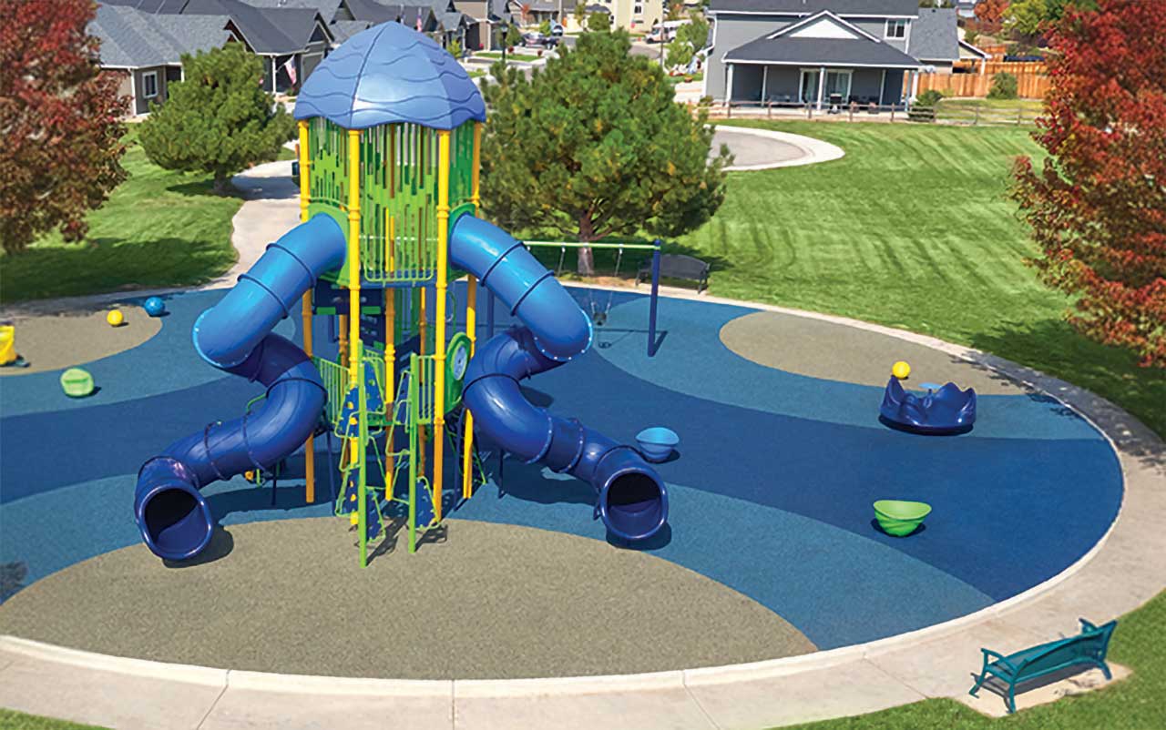 Tall playground tower with multiple spiral tube slides on poured-in-place surfacing.