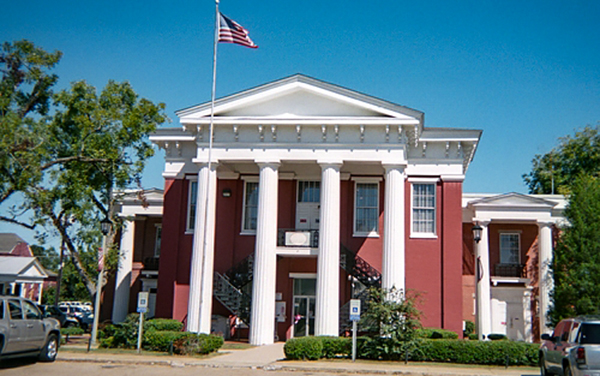 Wilcox County Courthouse, Camden, Alabama, with white columns and red exterior, for Bliss Products and Services.
