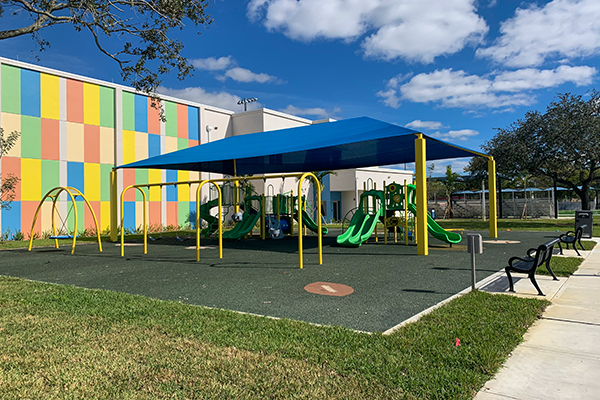 Shaded playground with poured in place rubber surfacing at Bunche Park Elementary in Miami Gardens, Florida, installed with support from Bliss Products and Services.