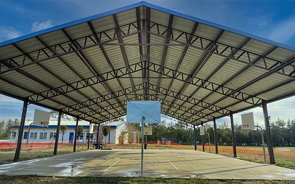 Gilchrist Elementary Covered Basketball Shelter Covered basketball court shelter at Gilchrist Elementary School providing shade over the concrete play area supplied by Bliss Products and Services