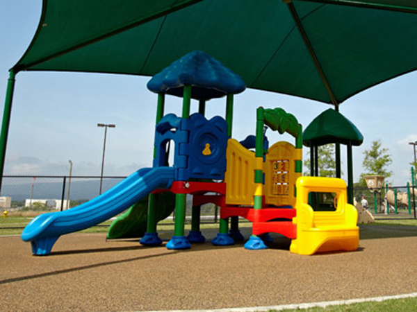 Early childhood toddler playground with bright play structure under shade by Bliss Products and Services
