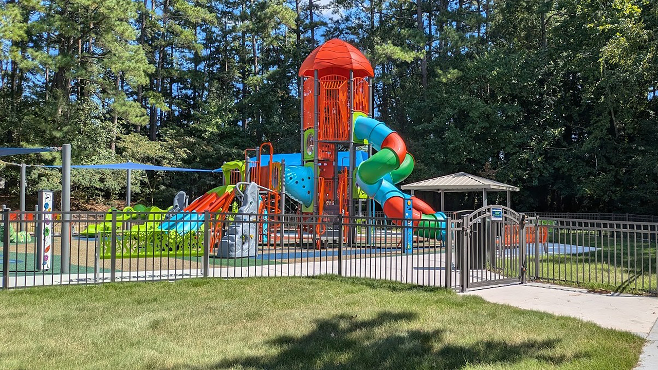 City of Durham new playground | Bliss Products and Services City of Durham playground with new sidewalks, a picnic shelter, a colorful play area for ages 2 to 5, a tall adventure zone for ages 5 to 12, and an ID Sculpture caterpillar detail in poured in place surfacing — Bliss Products and Services