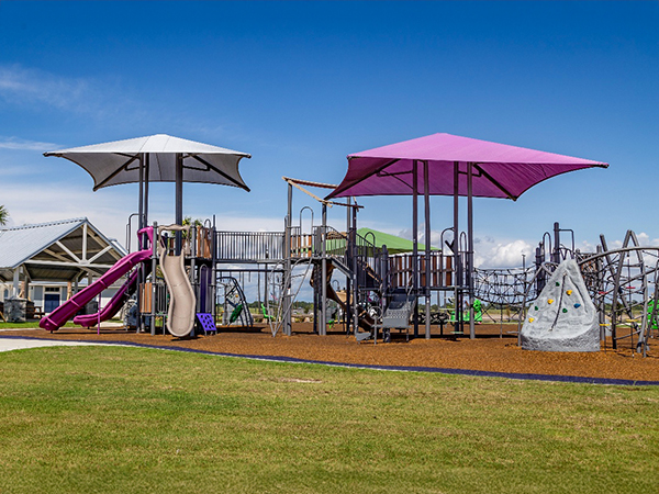 Shaded playground structures with slides and climbing features at Lakeshore Villages in Slidell, Louisiana, Bliss Products and Services.