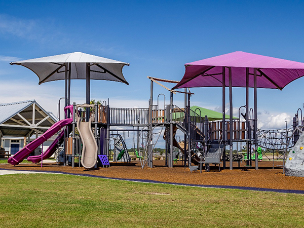 Shaded play structure with multiple slides and elevated decks at Lakeshore Villages in Slidell, Louisiana, Bliss Products and Services.