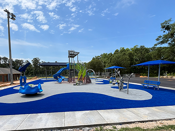 Inclusive, accessible playground in Miccosukee, Florida with blue safety surfacing, shade canopies, and play features, Bliss Products and Services