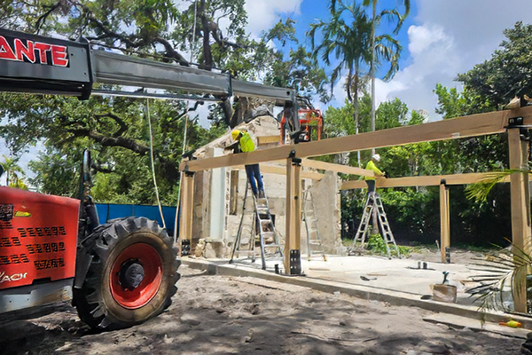 Construction equipment and timber framing during reconstruction of the Ben Butler Rock House Pavilion at Charles F. Vollman Park in Hollywood, Florida, with the preserved coral rock structure in the background. Bliss Products and Services.