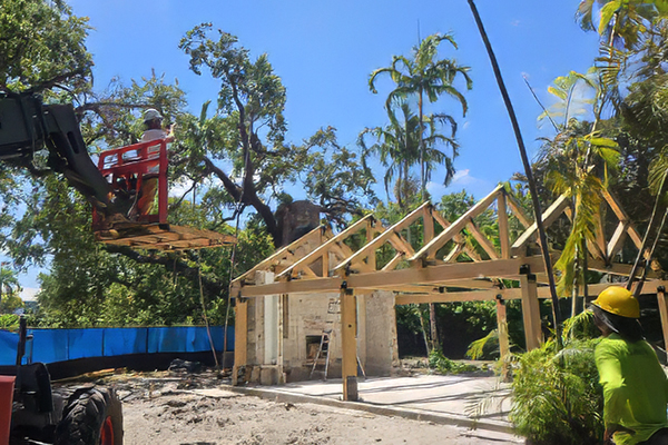 Crew setting roof trusses during reconstruction of the Ben Butler Rock House Pavilion at Charles F. Vollman Park in Hollywood, Florida, with the preserved coral rock structure on site. Bliss Products and Services.