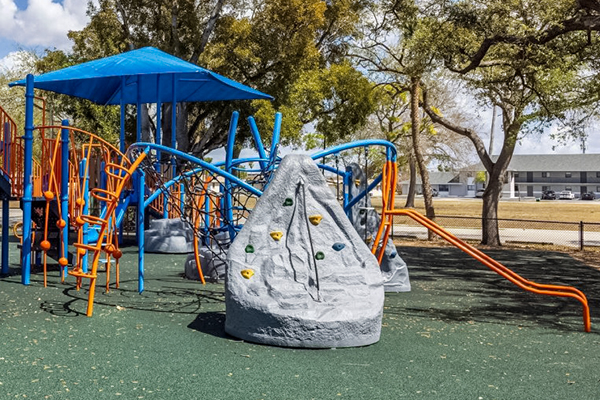 Playground climbing net and rock feature under shade canopy in Cape Coral Florida