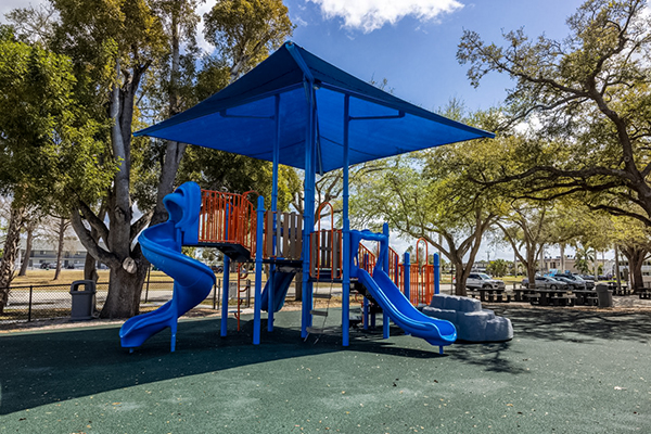 Playground structure with slides under blue shade canopy in Cape Coral Florida