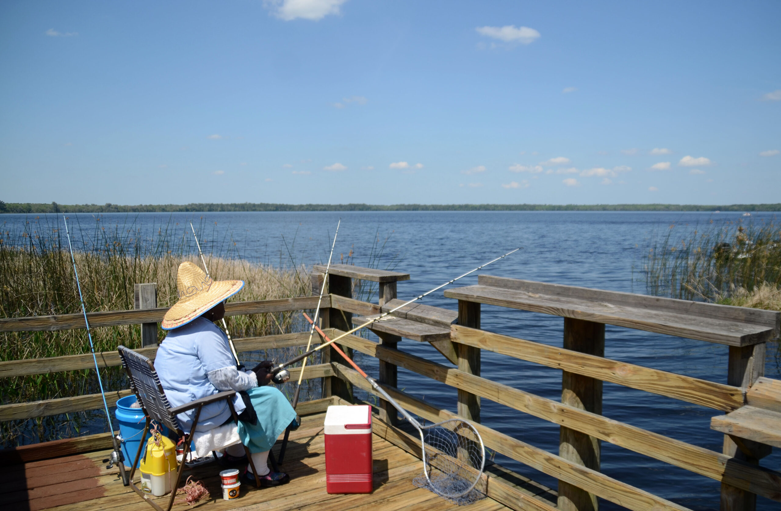 Person fishing from a wooden pier at Ocean Pond in Osceola National Forest, representing outdoor recreation in Baker County, Florida.