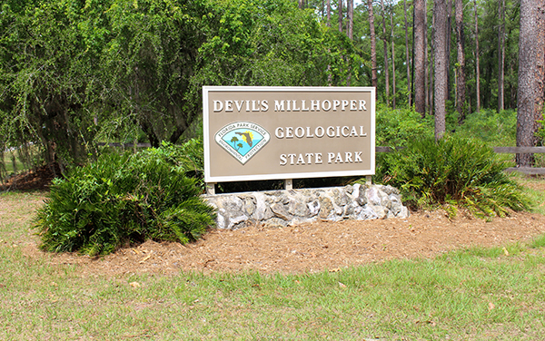 Devil’s Millhopper Geological State Park sign in Gainesville, Florida, representing natural recreation in Alachua County.