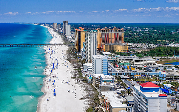 Aerial view of Panama City Beach in the Florida Panhandle with turquoise Gulf water, beachfront high-rises, and the pier, featured by Bliss Products and Services.