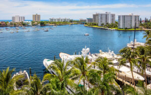 Boca Raton waterfront with boats, palms, coastal buildings, and marina views in southern Palm Beach County, Florida.
