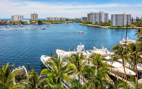 Boca Raton waterfront with boats, palms, coastal buildings, and marina views in southern Palm Beach County, Florida.