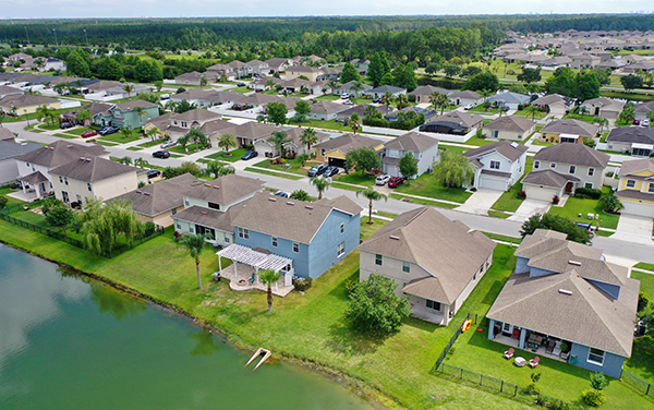 Aerial view of a Florida lakefront neighborhood with homes, trees, streets, lawns, and community green space.