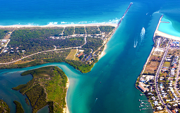 Aerial view of Fort Pierce Inlet in St. Lucie County, Florida, showing turquoise water, beaches, barrier island shoreline, and coastal waterways.