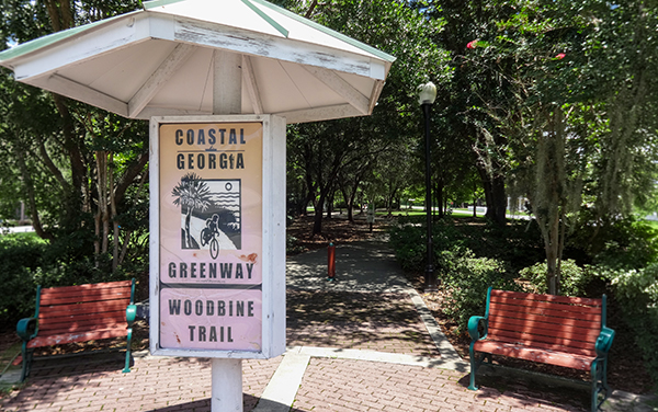Georgia Coast Rail-Trail sign and benches in Woodbine, Georgia, representing public trail and recreation space in Camden County.