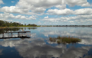 Lake Sebring with dock, shoreline, and cloud reflections in Highlands County, Florida