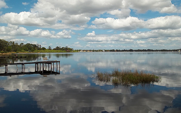 Lake Sebring with dock, shoreline, and cloud reflections in Highlands County, Florida