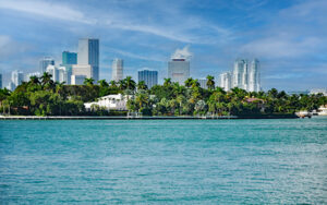 Miami skyline viewed from Biscayne Bay, with waterfront homes, palm trees, and high-rise buildings in Miami-Dade County, Florida.