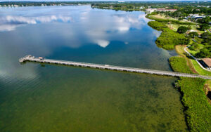 Aerial view of R.E. Olds Park in Oldsmar, Florida with a fishing pier, waterfront shoreline, green space, and Tampa Bay water.