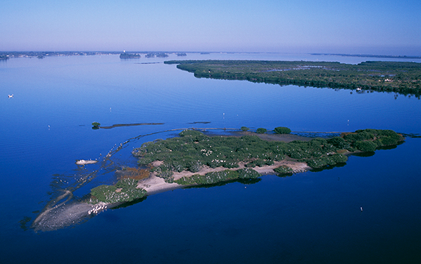 Aerial view of Pelican Island National Wildlife Refuge in Indian River County, Florida, surrounded by blue lagoon waters and coastal habitat.