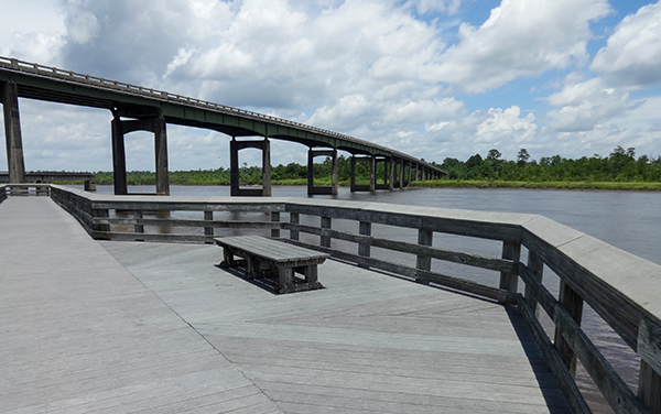 Satilla River Waterfront Park in Woodbine, Georgia, showing a boardwalk bench, river view, and public recreation space in Camden County.