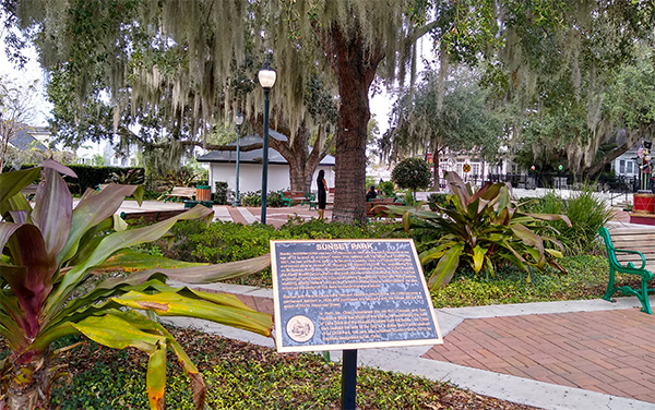 Sunset Park in Mount Dora, Lake County, Florida, with landscaped walkways, benches, and mature trees.
