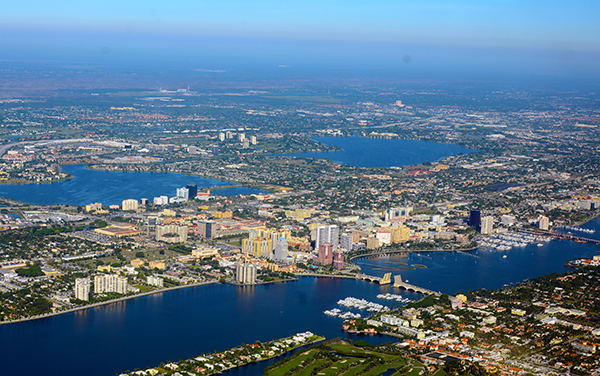Aerial view of West Palm Beach, Florida, showing downtown, the Intracoastal Waterway, bridges, marinas, and surrounding Palm Beach County communities.