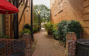 Brick walkway with landscaping, benches and downtown buildings at Baldwin Park in Americus, Georgia