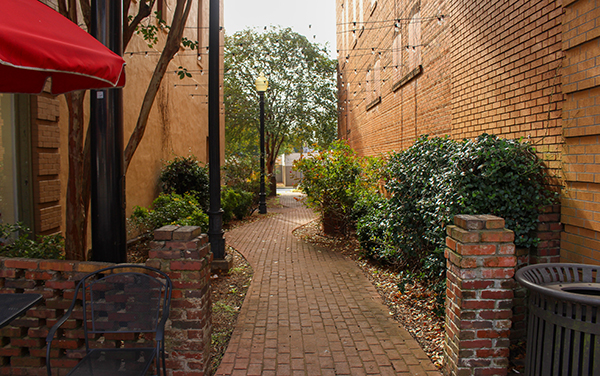 Brick walkway with landscaping, benches and downtown buildings at Baldwin Park in Americus, Georgia