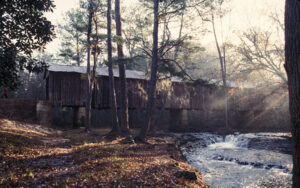 Historic Coheelee Creek Covered Bridge beside flowing water and woodland in Early County, Georgia