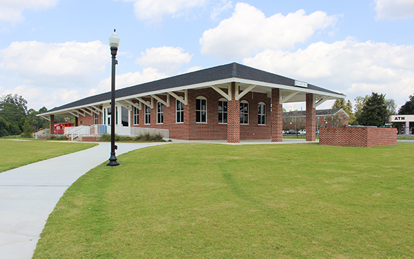 Historic brick Hahira Depot beside a paved walkway and landscaped lawn in Lowndes County, Georgia